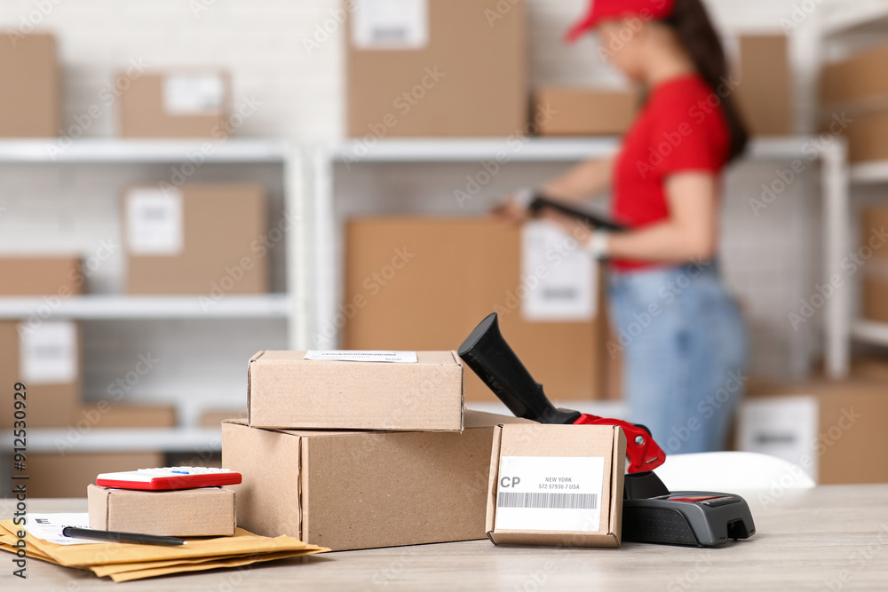 Fotografie Parcel boxes with packing tape dispenser on table at postal warehouse