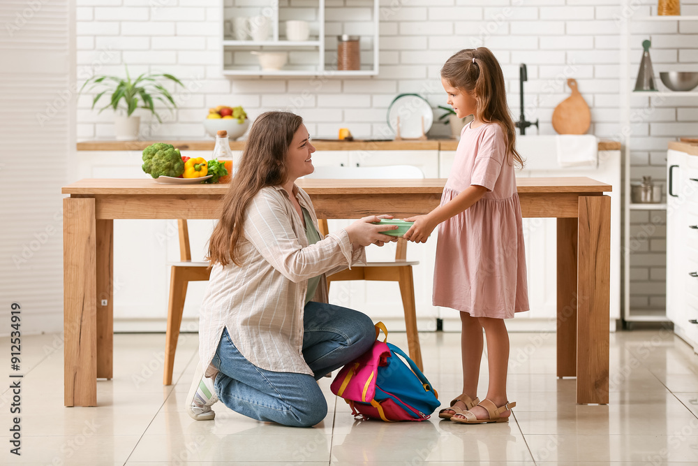 Mother with her daughter packing lunchbox for school in kitchen Mother with her daughter packing lunchbox for school in kitchen