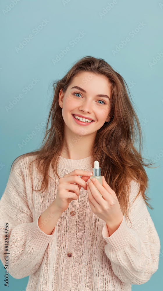 Beautiful young woman with radiant and glowing skin holds a serum bottle and looking at camera with happy smile. Blue background with copy space. Natural skin care concept Beautiful young woman with radiant and glowing skin holds a serum bottle and looking at camera with happy smile. Blue background with copy space. Natural skin care concept