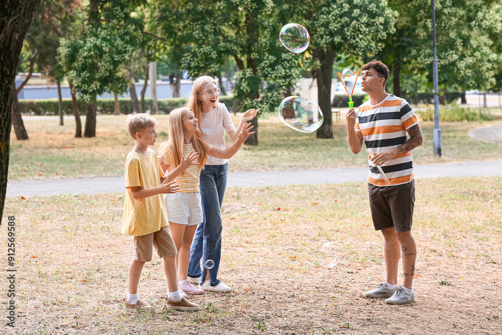 Fototapeta premium Happy family with cute children blowing soap bubbles in park
