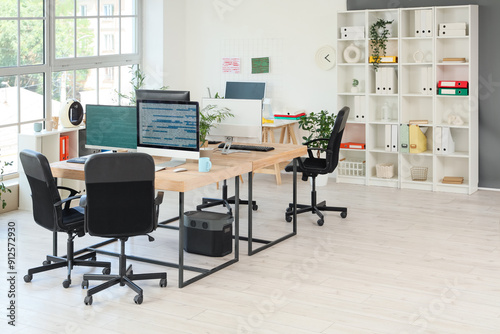 Interior of programmer's office with desks, shelf unit and plants photo