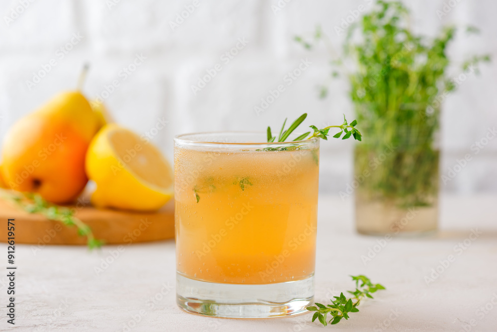 Fototapeta premium Pear lemonade with lemon, rosemary, thyme and ice on a light table. Healthy drink, sugar and alcohol free.