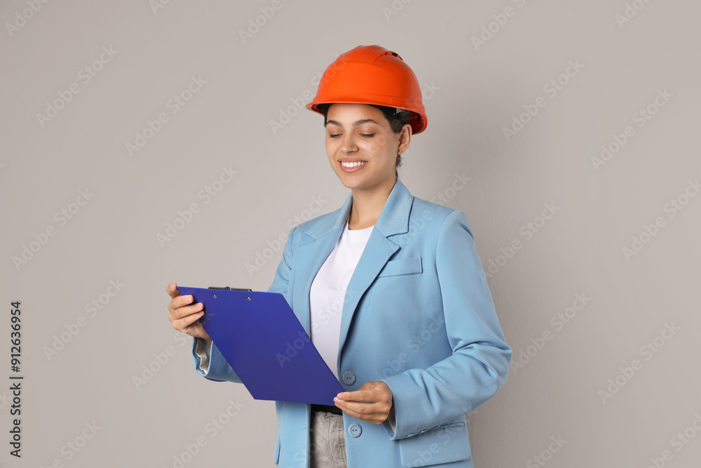Engineer in hard hat with clipboard on grey background Engineer in hard hat with clipboard on grey background