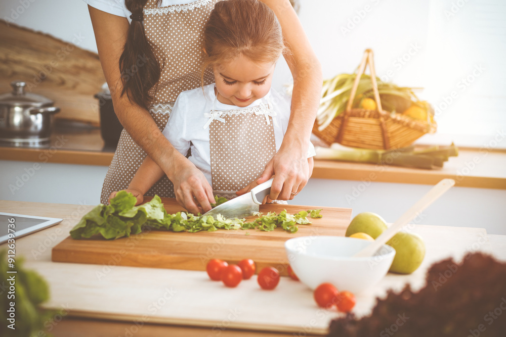 Happy woman and her daughter making healthy vegan salad and snacks for family feasting in sunny kitchen. Christmas, New year, Thanksgiving, Anniversary, Mothers Day. Healthy meal cooking concept Happy woman and her daughter making healthy vegan salad and snacks for family feasting in sunny kitchen. Christmas, New year, Thanksgiving, Anniversary, Mothers Day. Healthy meal cooking concept
