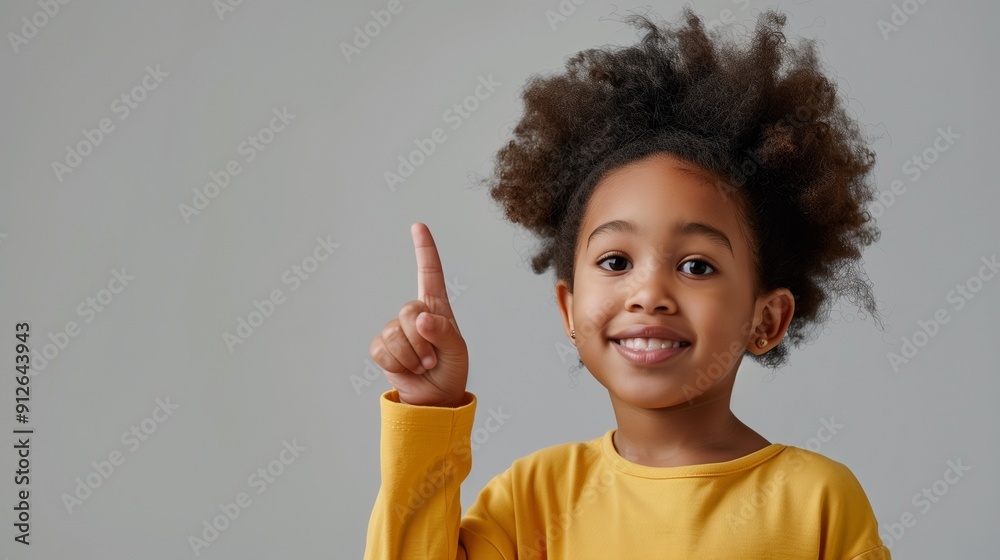 Idea warning and childhood concept - happy little african american girl pointing finger up over grey background. A.I.