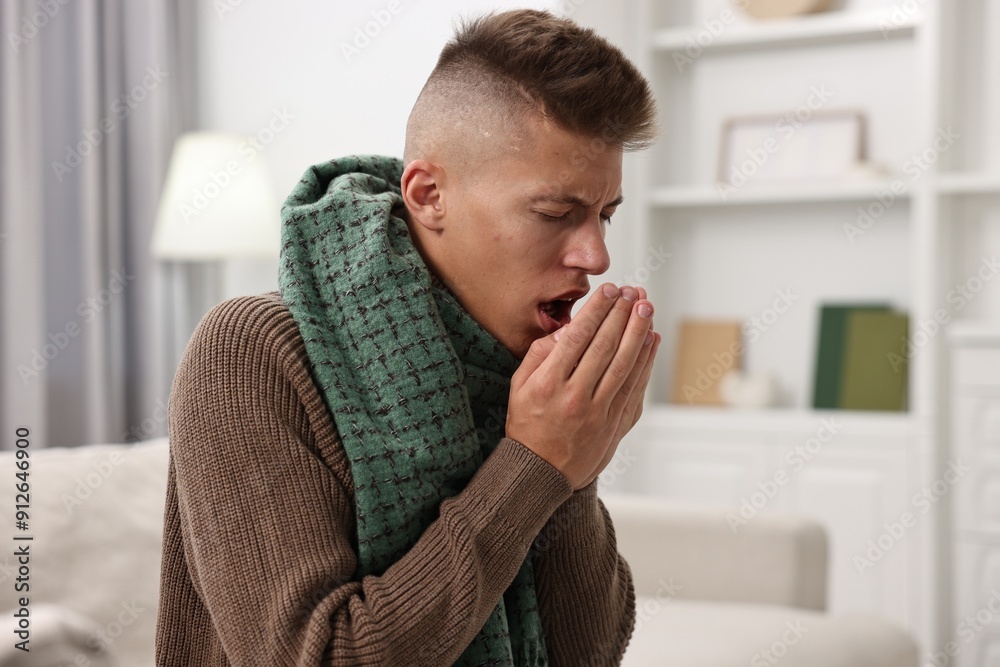 Cold symptom. Young man coughing at home Cold symptom. Young man coughing at home