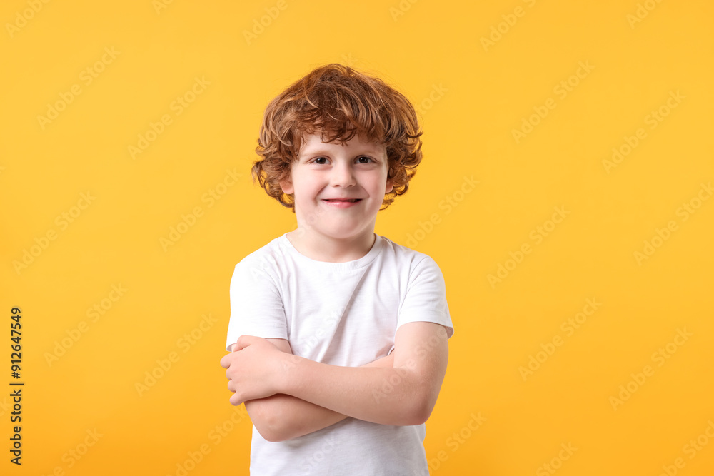 Portrait of cute little boy with crossed arms on orange background Portrait of cute little boy with crossed arms on orange background