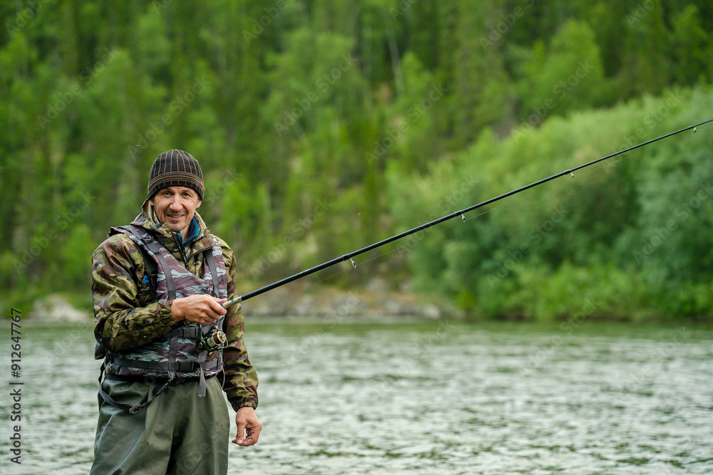 Fisherman with a fishing rod on a river against the background of a forest Fisherman with a fishing rod on a river against the background of a forest