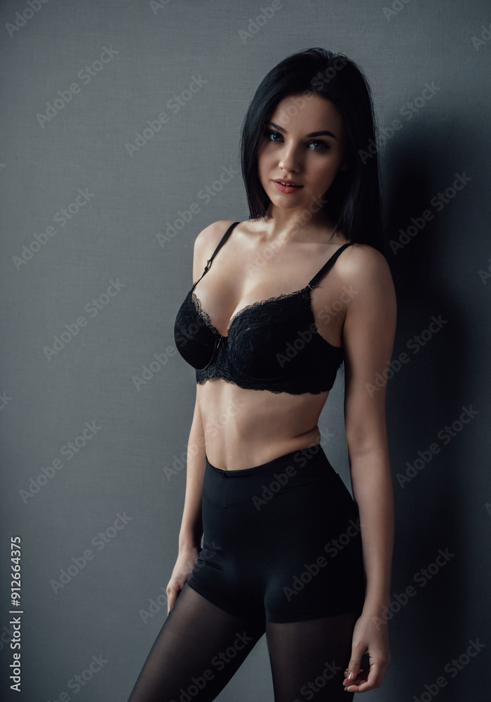 Fashion model posing in studio on plain gray background. Portrait of young woman with black hair. Fashion model posing in studio on plain gray background. Portrait of young woman with black hair.