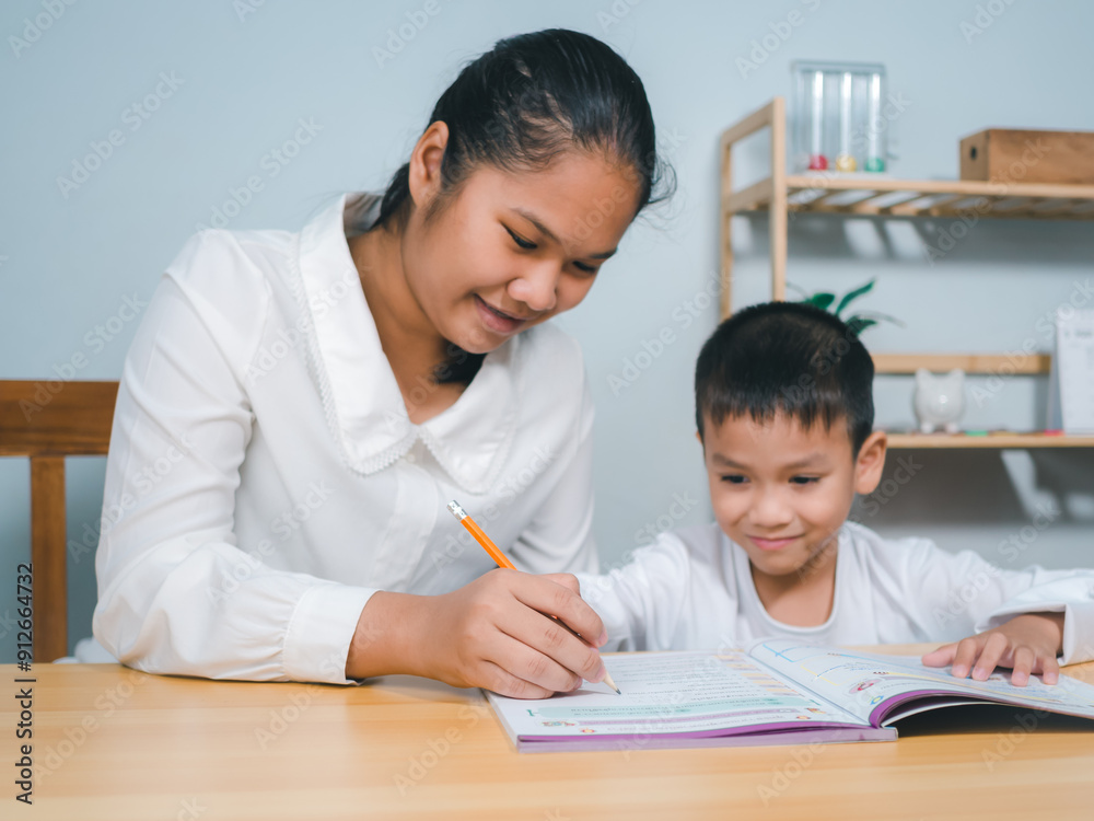 Female tutor helping little elementary school boy with homework during individual lesson at home, Teacher or mother helping boy writing lesson and learning to write, Education home school concept. Female tutor helping little elementary school boy with homework during individual lesson at home, Teacher or mother helping boy writing lesson and learning to write, Education home school concept.