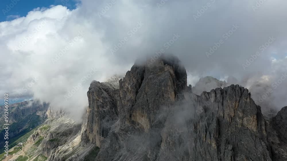Aerial view of Dolomites mountain peaks shrouded in clouds on a sunny day, South Tyrol, Italy