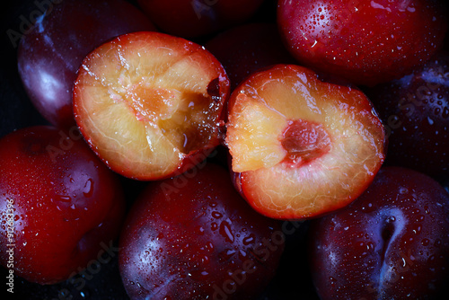 fresh plucked plum is cut into two halves	