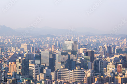 Photography Seoul city and skyscrapers in Gangnam district in the afternoon, with light fog and Bukhansan Mountain in the background, Seoul, South Korea