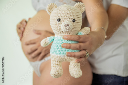 Couple with pregnant woman shows their future baby's teddy bear photo