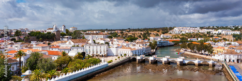 View on historic town of Tavira with Roman bridge over River Gilao, Algarve, Portugal. Cityscape of the Tavira old town with Clock tower, St Marys church, Algarve region, Portugal.