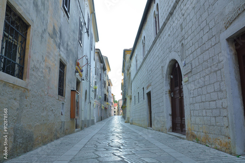 A narrow cobblestone street lies nestled between two historic stone buildings