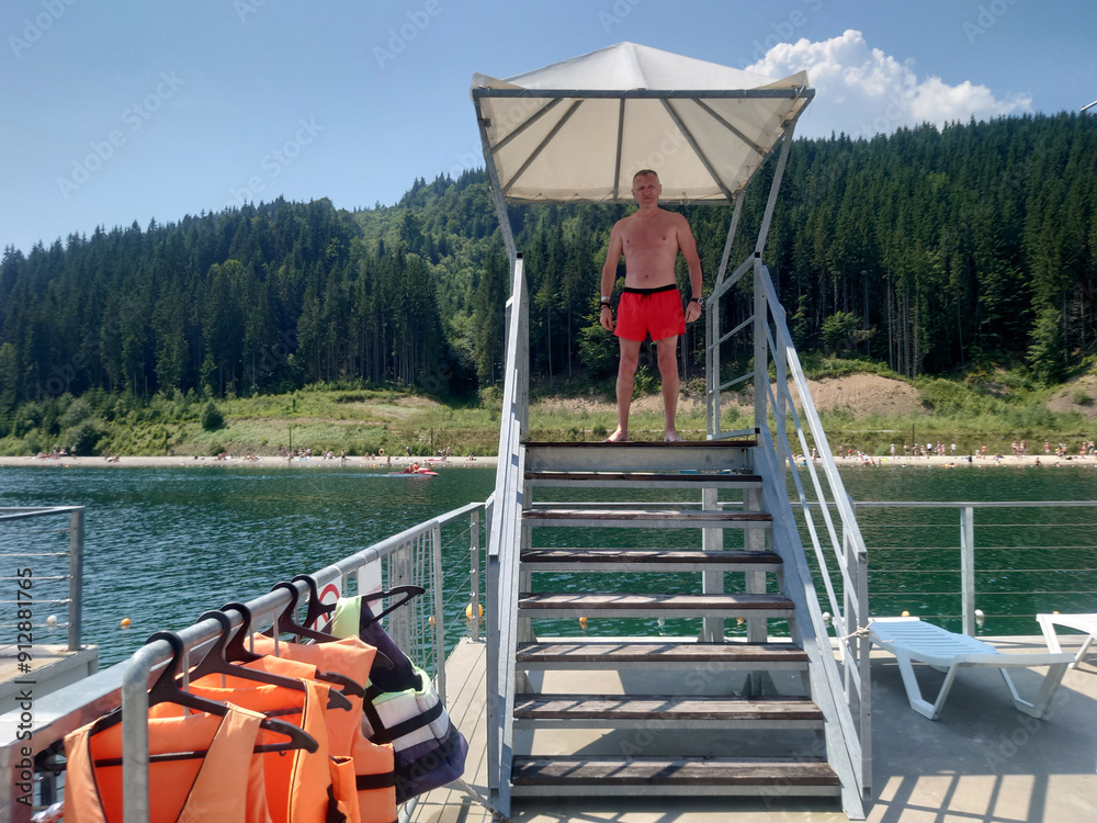 A lifeguard on the beach looks at the camera.