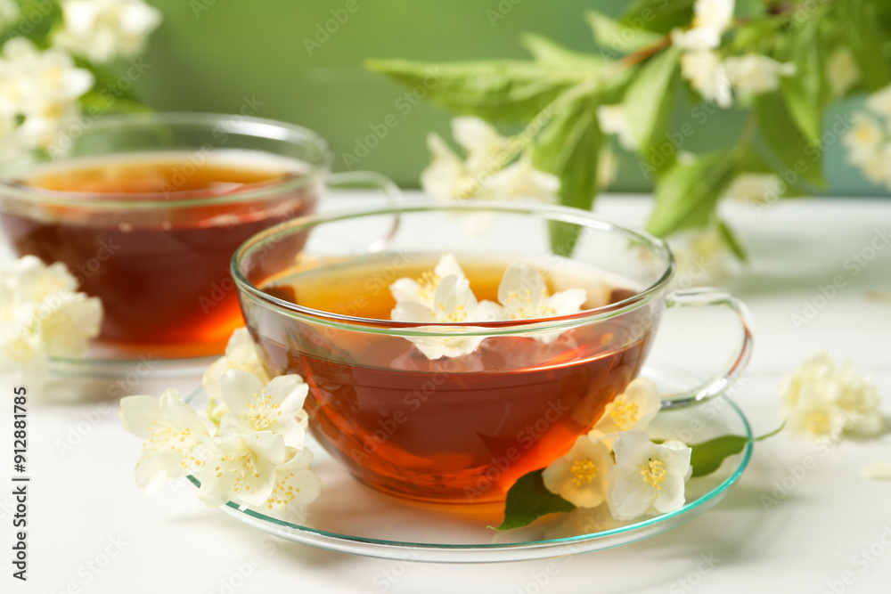 Hot jasmine tea in cup and flowers on white marble table Hot jasmine tea in cup and flowers on white marble table