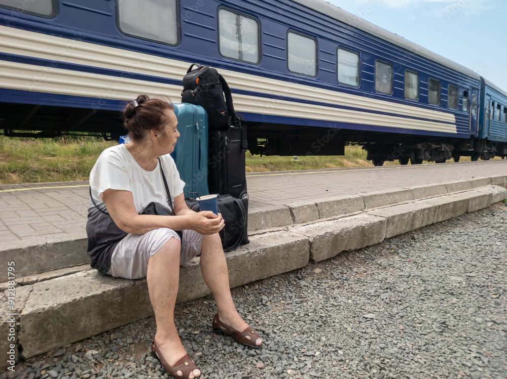 A woman sits near her luggage on the platform.