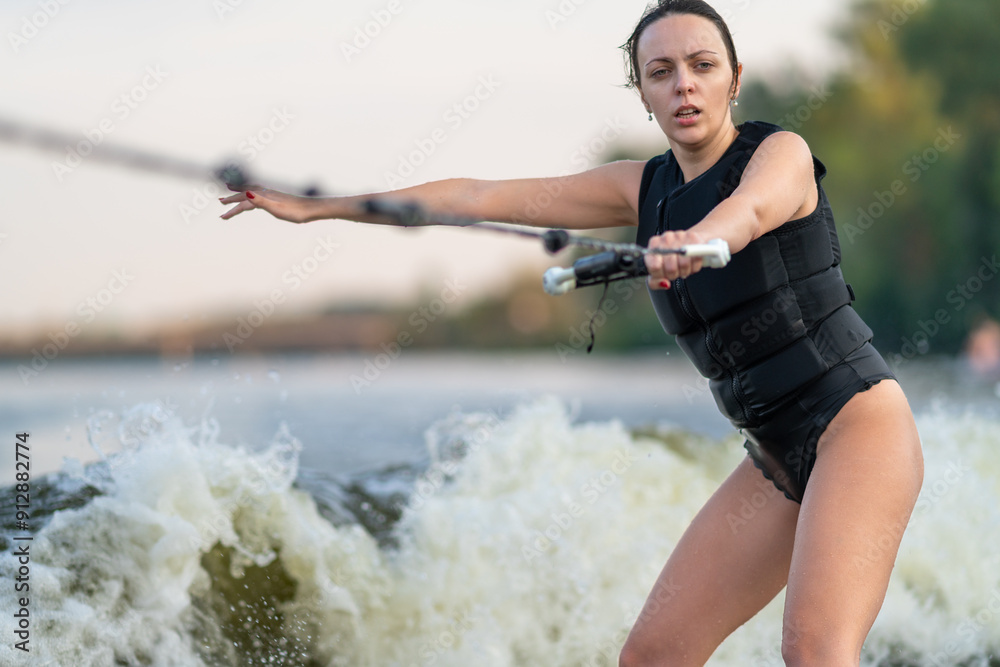 Young female surfing holding on to a rope.