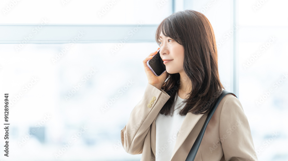 Fototapeta premium スマートフォンで話す笑顔の日本人ビジネスウーマン