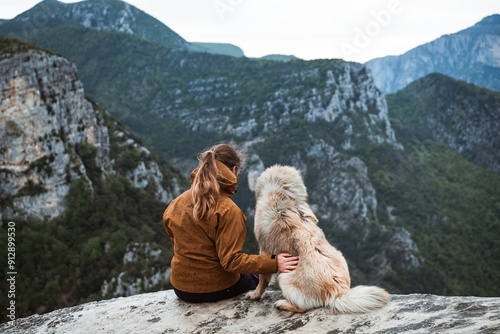 Junge Frau sitzt an der Verdonschlucht mit Blick aufs Tal in Mitten der Natur, genießt die aussicht und kuschelt mit ihrem Eurasier photo