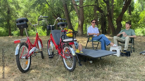 Family bike ride in the park. Mother with two sons riding bicycles on the path in summer. Simferopol, Crimea photo