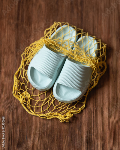 pair of light colored slippers is placed on yellow net atop rustic wooden surface, evoking summer vibe perfect for casual outings. Top view. Copy Space. High quality photo photo