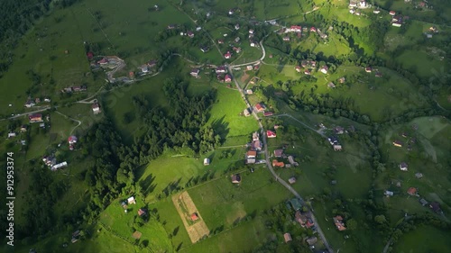 High angle flyover footage over the magnificent picturesque village of Magura in Brasov region of the Romanian Carpati mountains. Drone shot of the gem of romanian tourism on a green summer day.
 photo