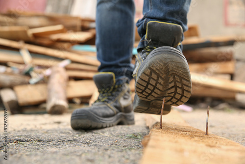 Careless worker stepping on nail in wooden plank outdoors, closeup