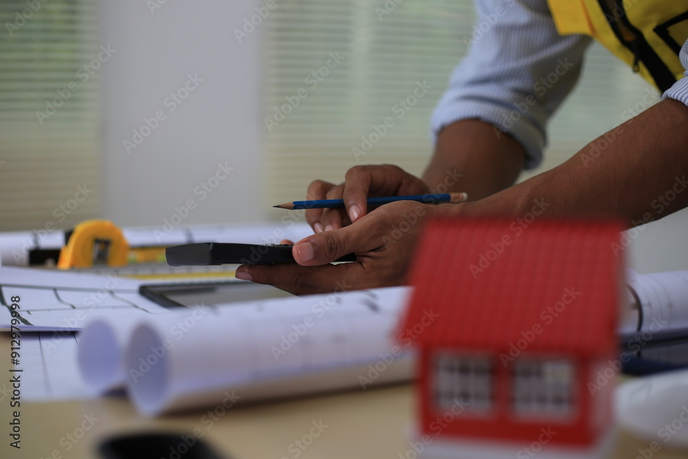 Fototapeta premium Asian architect and designer using blueprints and laptop to draw building structure in office. Construction concept, Engineering concept, Building plan, Building permit, Home architecture, Engineering