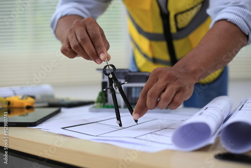 Asian architect and designer using blueprints and laptop to draw building structure in office. Construction concept, Engineering concept, Building plan, Building permit, Home architecture, Engineering