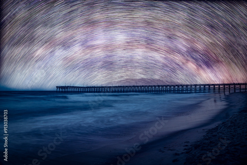 Star trails over an ocean pier and beach