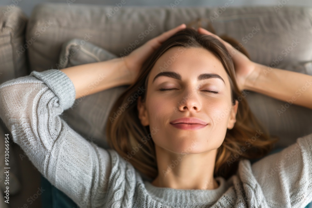 Fototapeta premium A woman is laying on a couch with her head on her hand. She is smiling and she is relaxed