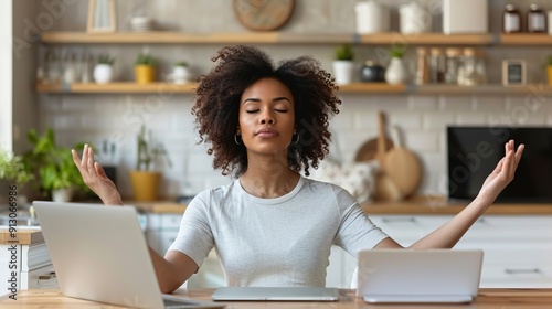 Woman meditating with two laptops in bright kitchen
