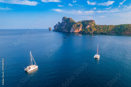 Tourist boat trip in Thai travel concept. Aerial view landscape with sunrise on Nui beach with white yacht catamaran in Phi Phi Don Thailand. photo