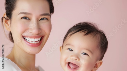 Warm and joyful bond between an Asian mother and her happy baby, captured in a light studio setting.