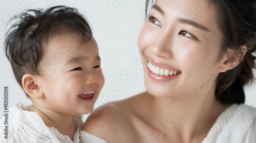 Heartfelt studio portrait of an Asian mother and her joyful baby, reflecting their loving connection.