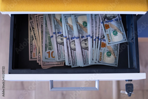 A pile of hundred dollar bills in a drawer with key lock