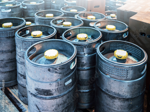 Stacked beer kegs at brewery yard, robust supply chain and storage of craft beer in industrial metal barrels with visible wear and tear. photo