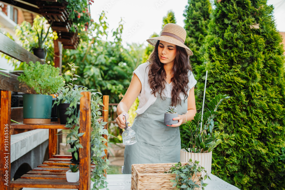 Obraz premium Young woman taking care of plants with water can and mister
