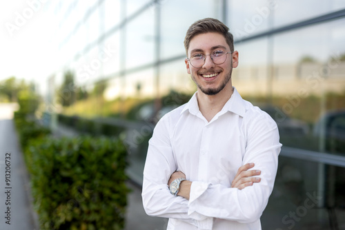 young man with glasses in front of the glass building