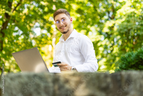 young man with glass in park buys online