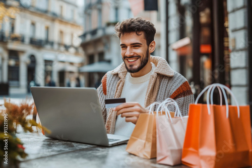 Young Man Enjoying Online Shopping At A Café With Colorful Shopping Bags