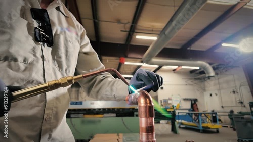 Pipefitter using an oxyacetylene torch brazing copper pipe