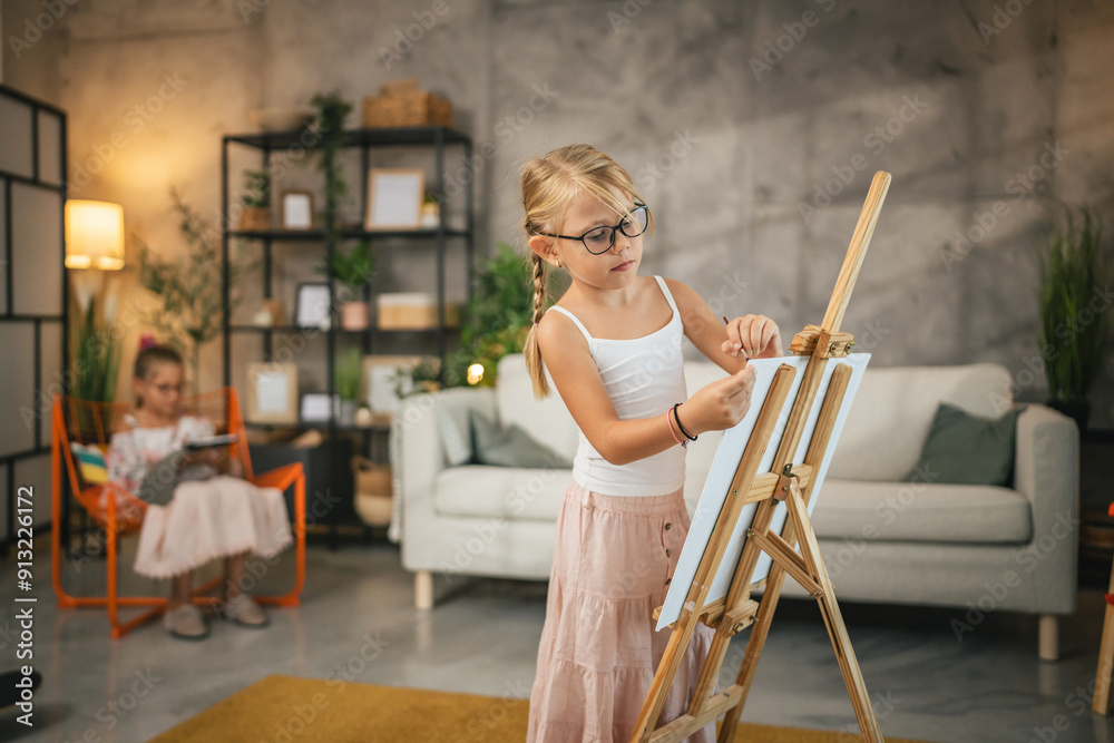 young girl child paint on canvas easel with brush and water color at home young girl child paint on canvas easel with brush and water color at home