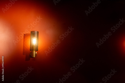 Elegant wall light fixture illuminating dark red room at night.