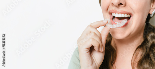 Smiling Woman Inserting Clear Teeth Aligner