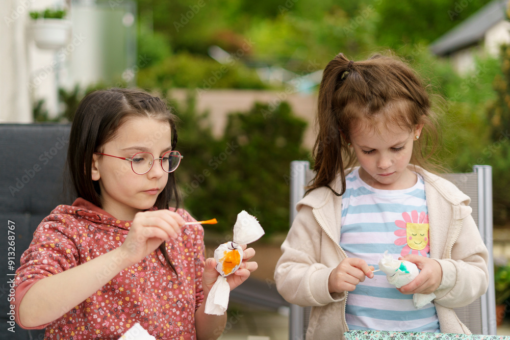 Two little girls making crafts sitting at a table in the backyard of their home. Children's creative concept Two little girls making crafts sitting at a table in the backyard of their home. Children's creative concept