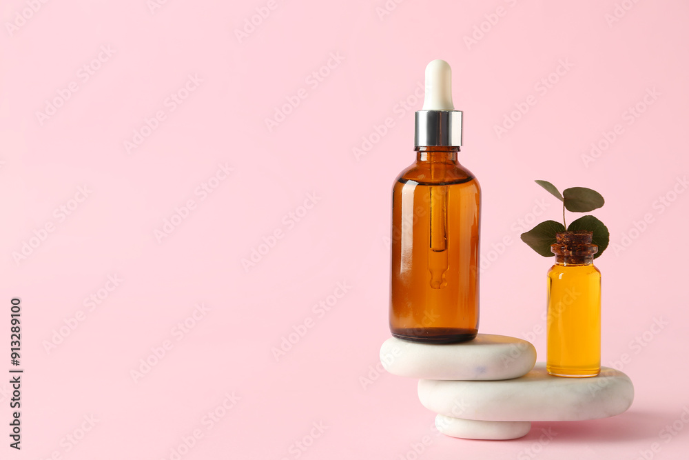 Bottles of cosmetic oil with stones on pink background Bottles of cosmetic oil with stones on pink background